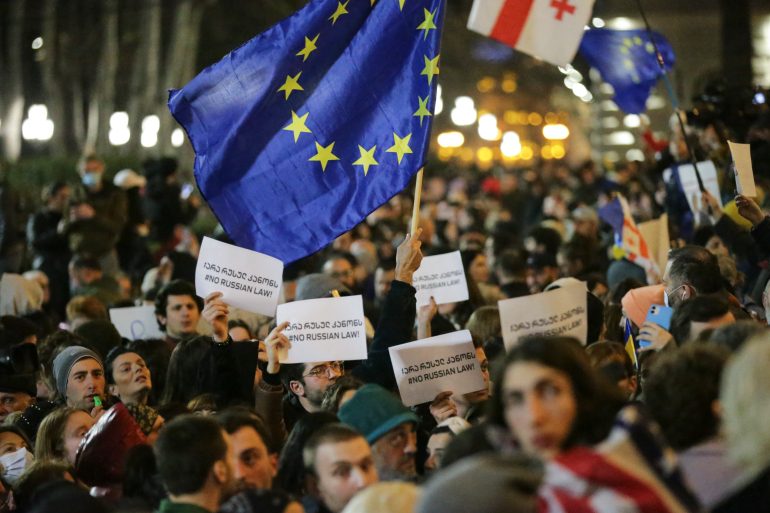 Manifestantes en Tiflis sostienen pancartas y la bandera de la Unión Europea 