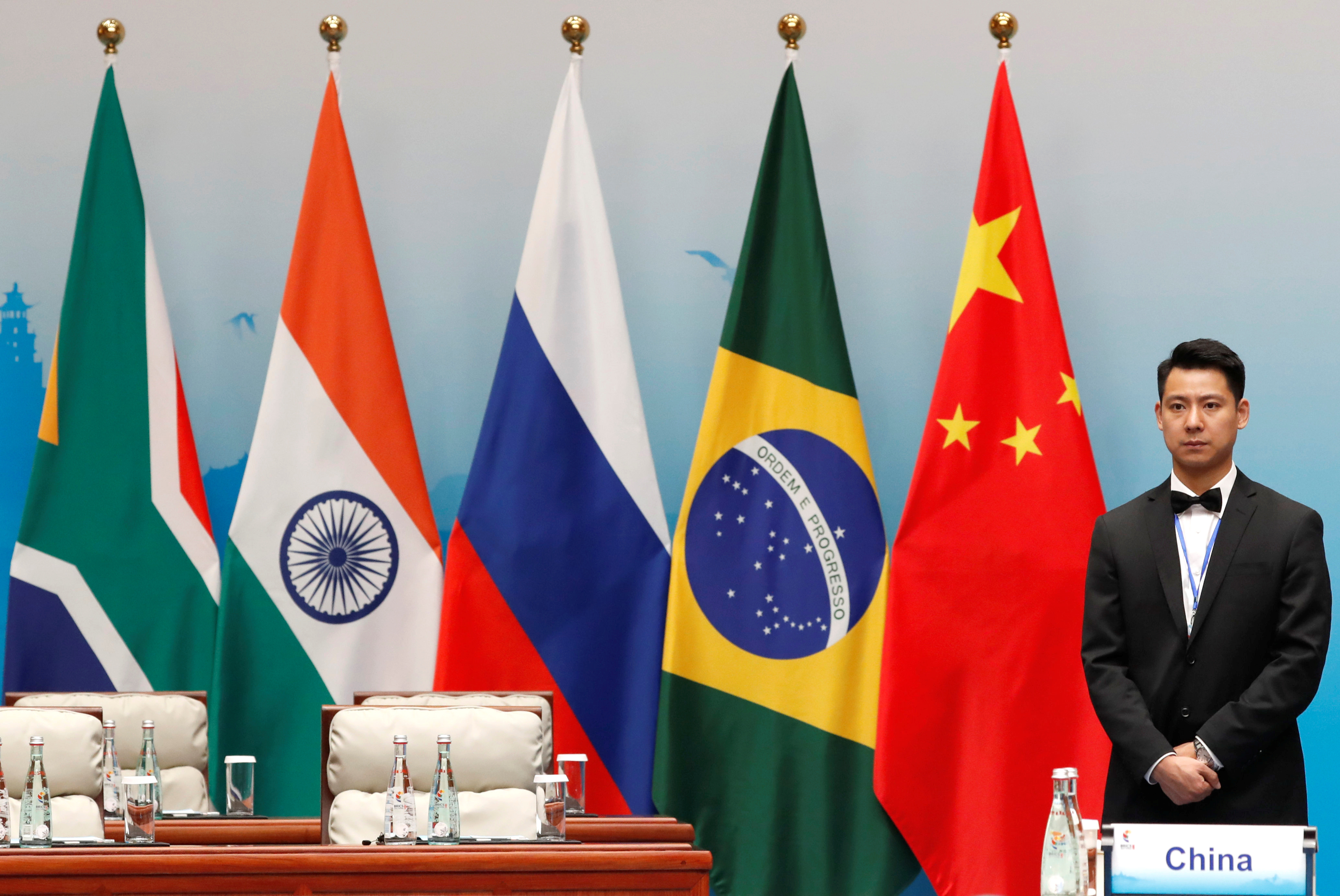 Un asistente junto a las banderas de Sudáfrica, India, Rusia, Brasil y China durante la sesión plenaria de la cumbre BRICS, en Xiamen.