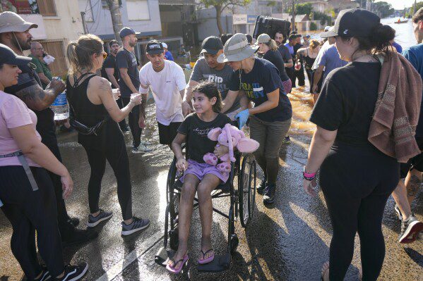 Voluntarios empujan una silla de ruedas que transporta a un evacuado de un área inundada por fuertes lluvias, en Porto Alegre, Brasil, el martes 7 de mayo de 2024. (Foto AP/Andre Penner)