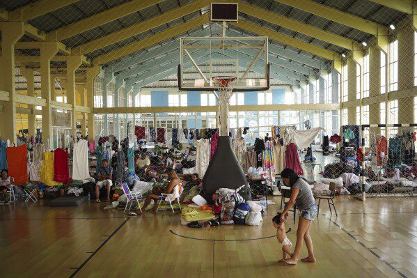 Residentes descansan en un gimnasio convertido en refugio para personas cuyas casas quedaron inundadas por las fuertes lluvias, en Canoas, estado de Rio Grande do Sul, Brasil, el 8 de mayo de 2024. (Foto AP/Carlos Macedo)