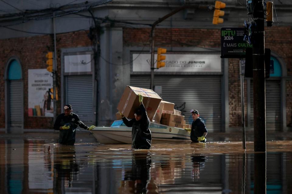 Foto: Hombres cargan y mueven paquetes a lo largo de una calle inundada en el centro histórico de Porto Alegre, estado de Rio Grande do Sul, Brasil, 14 de mayo de 2024. (Anselmo Cunha/AFP vía Getty Images)